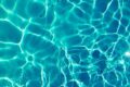 Bright turquoise water surface in sunlight, capturing shimmering patterns and reflections.