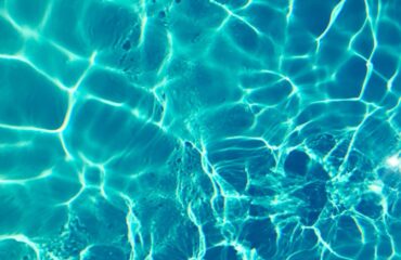 Bright turquoise water surface in sunlight, capturing shimmering patterns and reflections.
