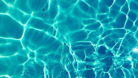 Bright turquoise water surface in sunlight, capturing shimmering patterns and reflections.
