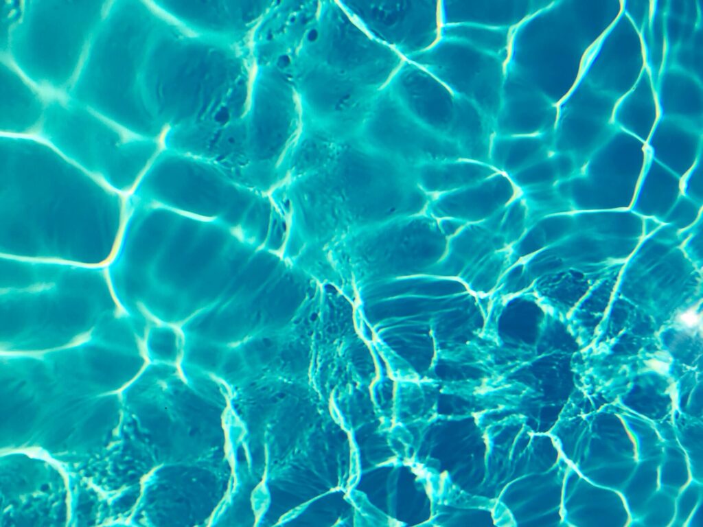 Bright turquoise water surface in sunlight, capturing shimmering patterns and reflections.